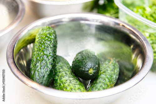 Fresh cucumbers lying with steel bowl.