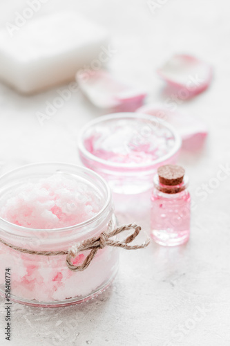 body treatment with rose petals and cosmetic set white desk background