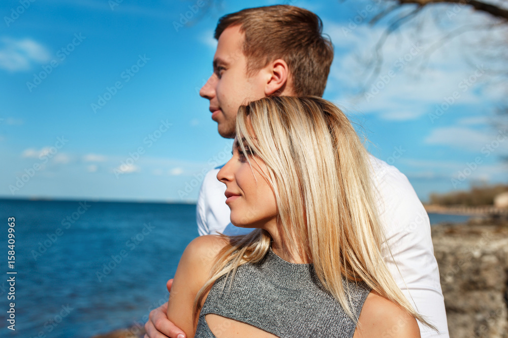 Happy couple on sea background. Happy young couple laughing and hugging on the beach Happy couple on sea background. Happy young couple laughing and hugging on the beach