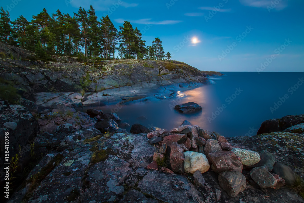Moon path on the water. Rocky coast. Wild nature. Pines on the shore. Pines on the rock. Karelia. Ladoga lake.