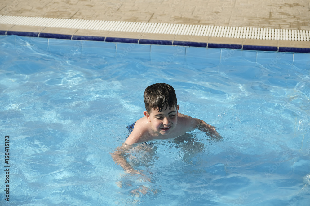Caucasian boy having fun inside swimming pool during summer time