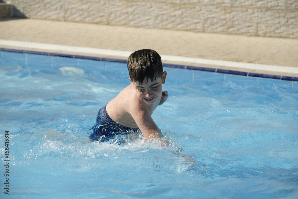 Caucasian boy having fun inside swimming pool during summer time Caucasian boy having fun inside swimming pool during summer time