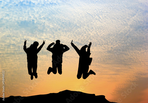 Group of happy young people jumping on the mountain at sunrise