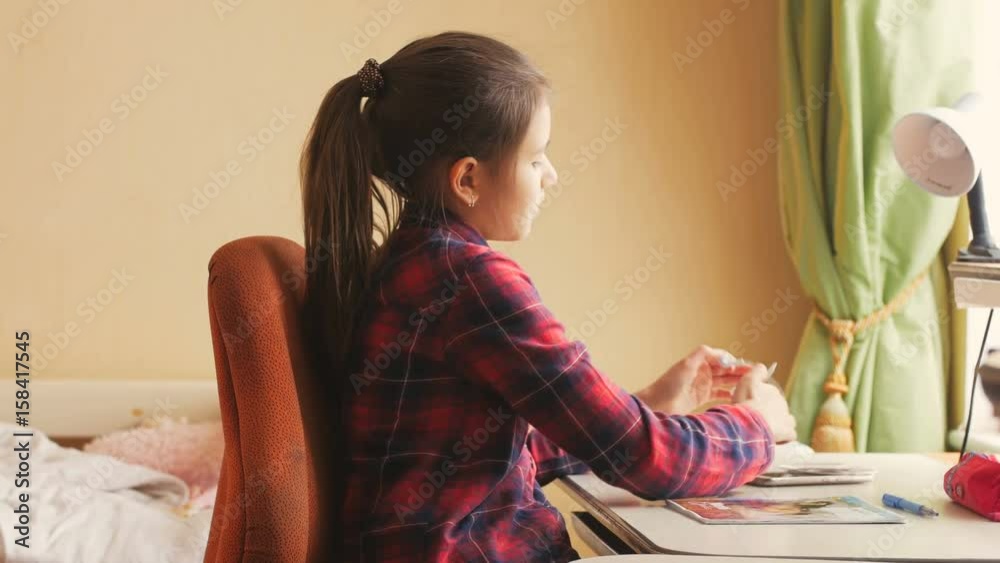 4k video of beautiful girl finished doing homework and relaxing behind desk 4k video of beautiful girl finished doing homework and relaxing behind desk