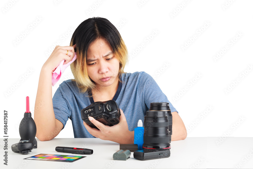 Asian woman cleaning a camera with cloth and photography equipment on table. object isolated on white background with clipping path and copy space. Asian woman cleaning a camera with cloth and photography equipment on table. object isolated on white background with clipping path and copy space.
