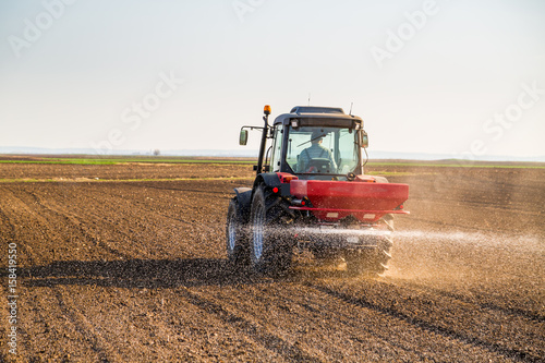 Farmer fertilizing arable land with nitrogen, phosphorus, potassium fertilizer photo