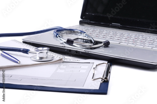 Stethoscope with clipboard and laptop on the desk