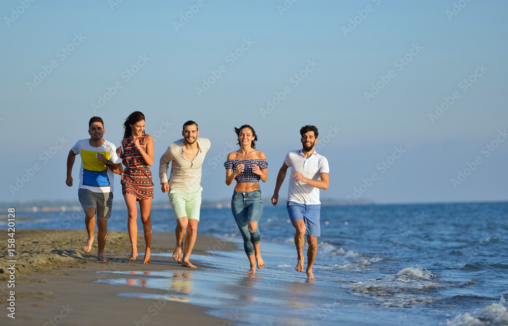 Group of friends having fun walking down the beach at sunset Group of friends having fun walking down the beach at sunset