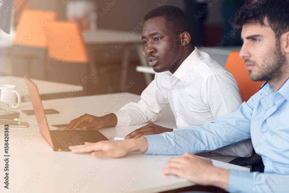 Image of two young businessmen interacting at meeting in office Image of two young businessmen interacting at meeting in office
