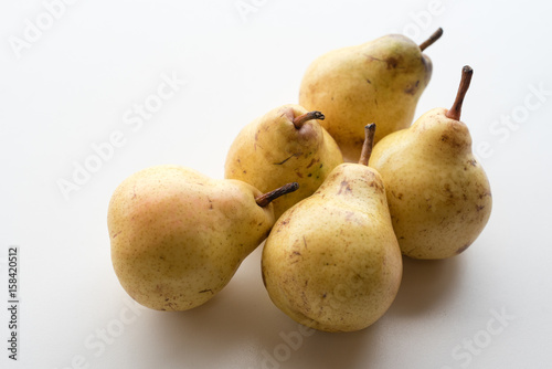 Close up view of natural looking yellow bartlett pears clustered together on white table (selective focus)