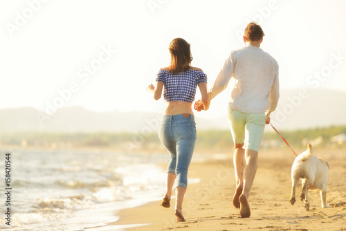 two young people running on the beach kissing and holding tight with dog © FS-Stock