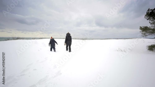 mother and kid walking on beach ontario canada in winter with snow