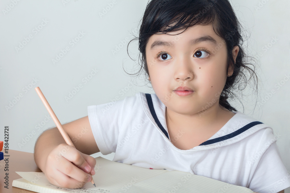 Beautiful little girl looking focused and concentrated on doing her homework Beautiful little girl looking focused and concentrated on doing her homework