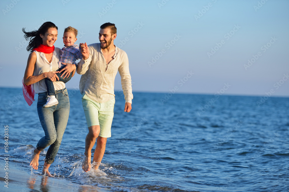 happy young family have fun on beach run and jump at sunset