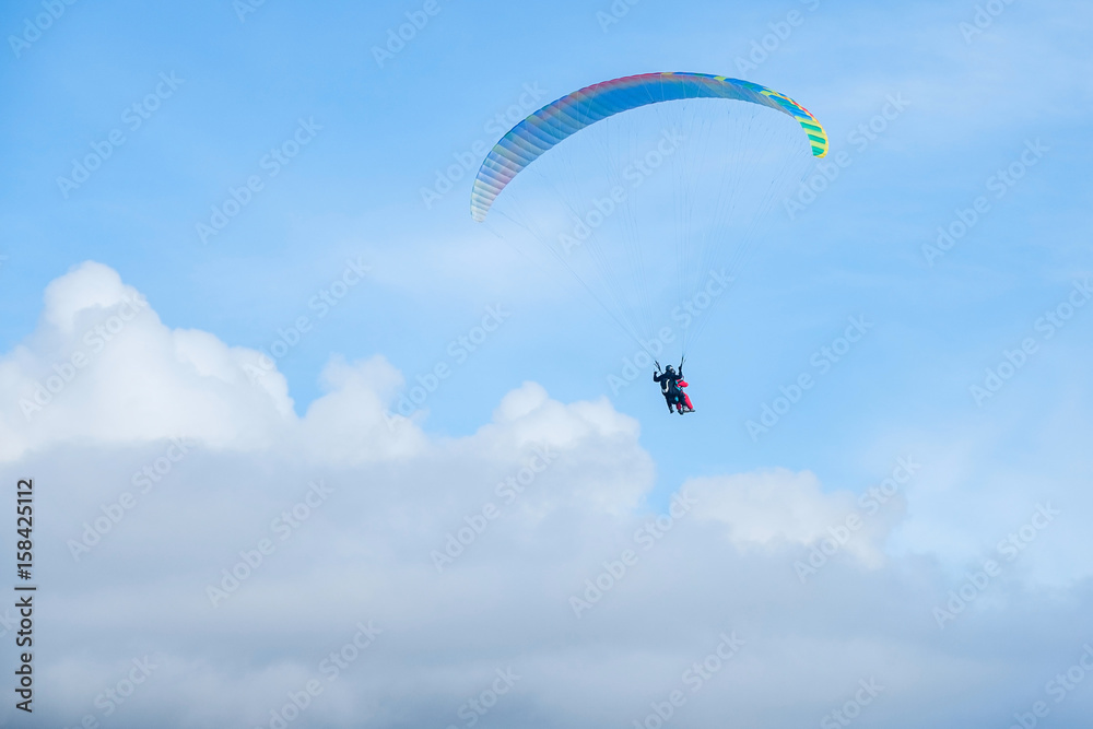 Paragliders in bright blue sky, tandem of instructor and beginner Paragliders in bright blue sky, tandem of instructor and beginner
