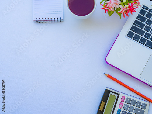 Flat lay, top view office table desk frame. feminine desk workspace with office accessories including laptop, note book, red pencil, coffee cup, calculator and flower on white background.