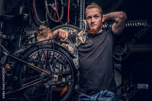 Bicycle mechanic in a workshop with bike parts and wheel on a background.