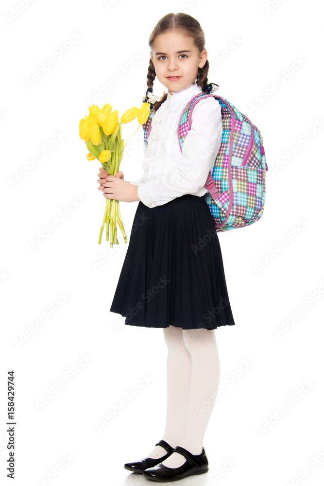 A schoolgirl with a bouquet of flowers and a backpack on her sho A schoolgirl with a bouquet of flowers and a backpack on her sho