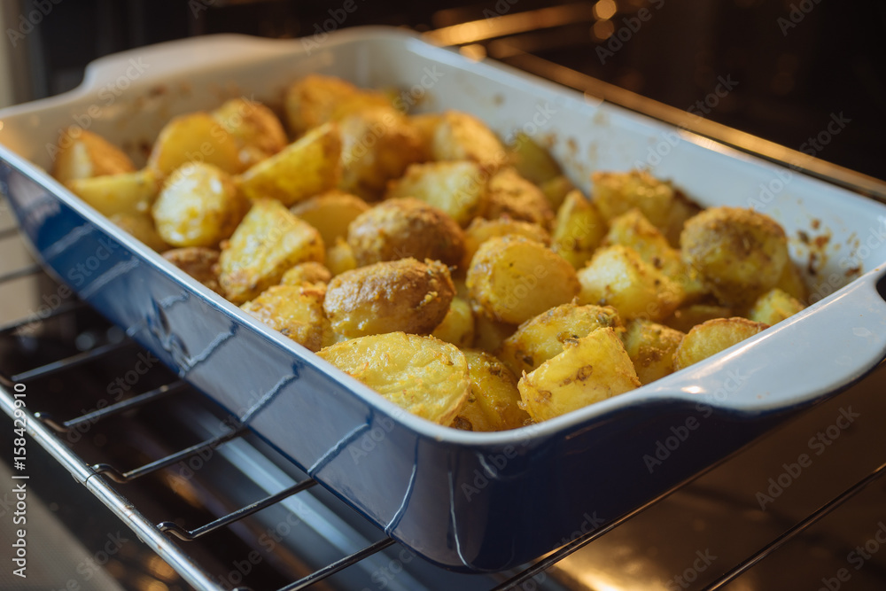 Closeup on baking potatoes with curcuma and other spices in roasting pan Closeup on baking potatoes with curcuma and other spices in roasting pan