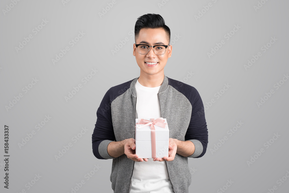 Portrait of asian young man holding gift box isolated over gray background Portrait of asian young man holding gift box isolated over gray background