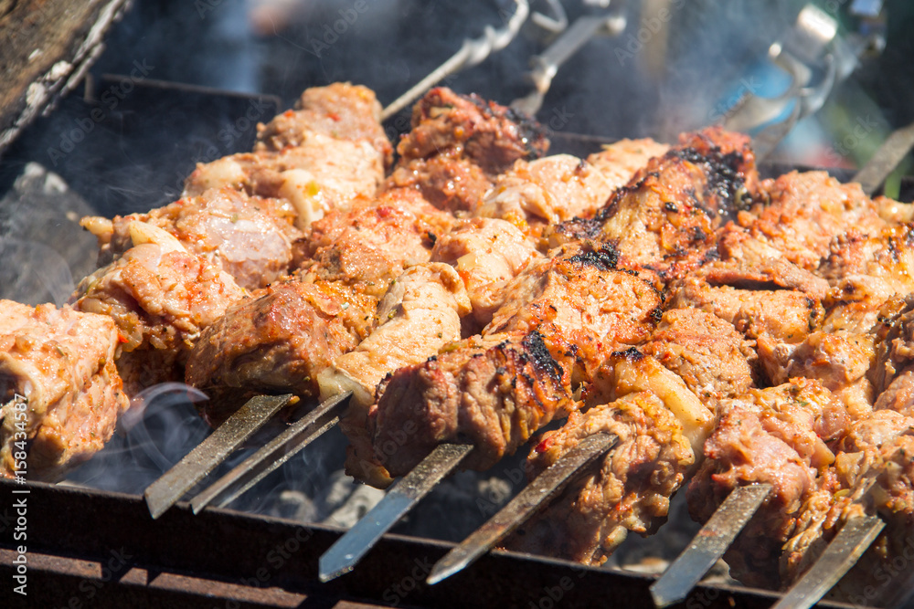 Grilled kebab cooking on metal skewer. Roasted meat cooked at barbecue.Traditional eastern dish, shish kebab. Grill on charcoal and flame, picnic, street food