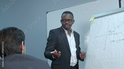 Afro-american businessman making presentation of a business plan on the flipchart