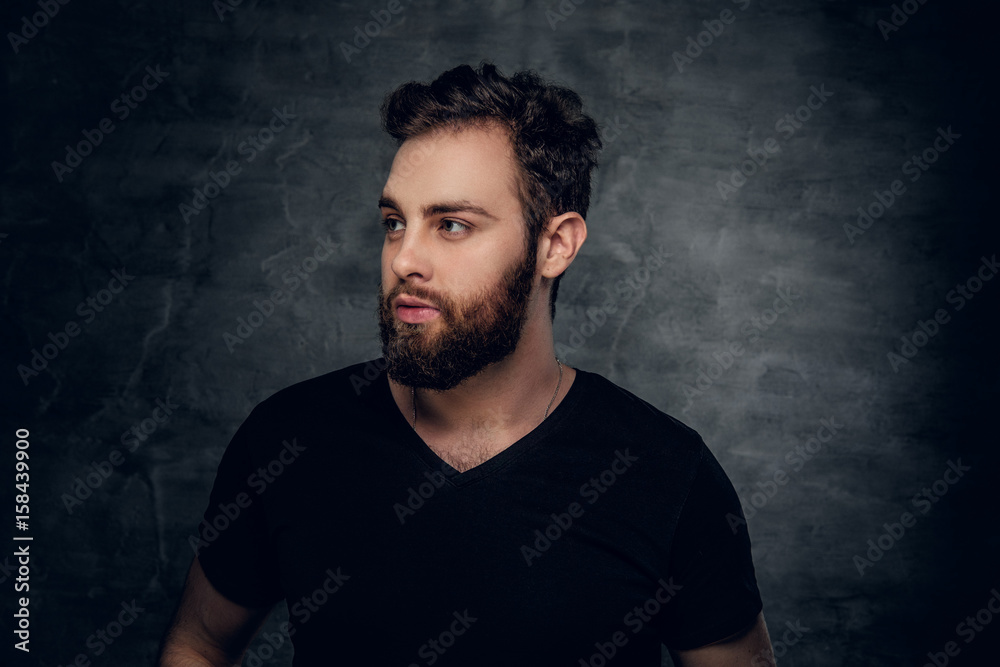 Bearded male in a black t shirt over grey background.