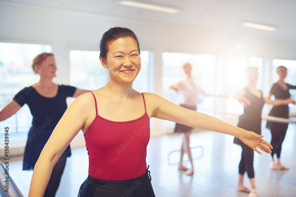 Adult Asian ballerina dancing in class and looking at camera