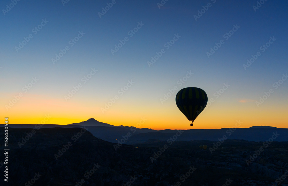 Hot air balloon flying over valley at sunrise. Cappadocia. Turkey