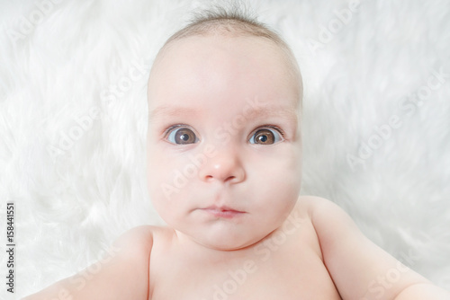 Cute baby lies on a white fluffy background