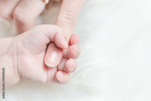 Hand of a baby holds a woman's finger