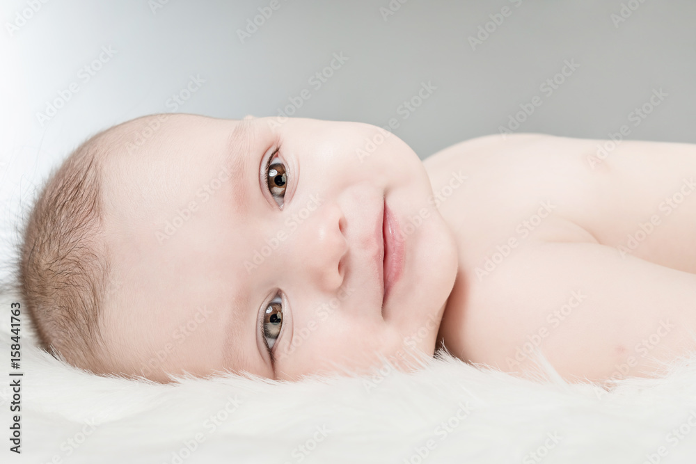 Smiling cute baby lies on a white fluffy background Smiling cute baby lies on a white fluffy background