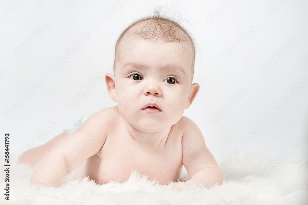 Cute baby lies on a white fluffy background Cute baby lies on a white fluffy background