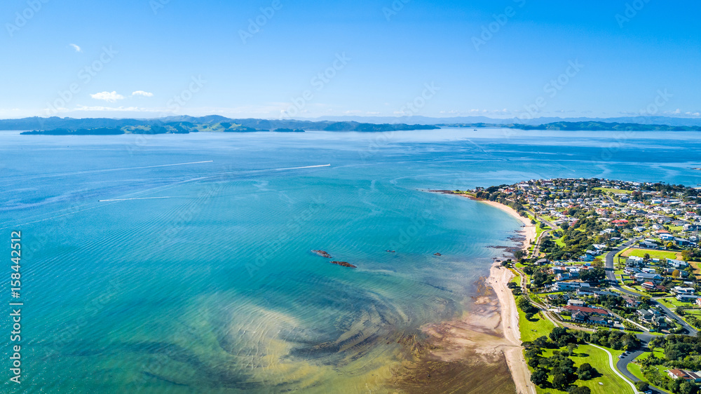 Aerial view on sunny beach with residential suburb on the background. Auckland, New Zealand. Aerial view on sunny beach with residential suburb on the background. Auckland, New Zealand.
