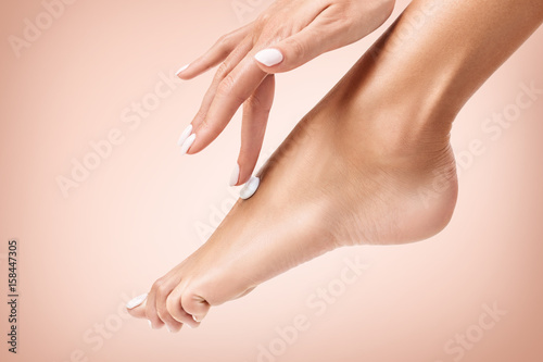 Woman applying cream on her beautiful feet.