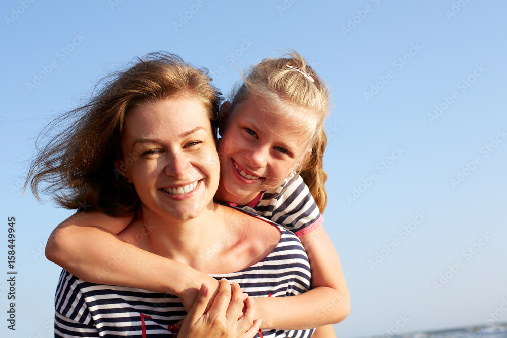 Happy mother and daughter laughing together outdoors. Closeup