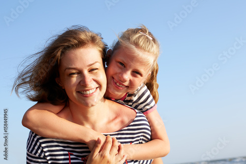 Happy mother and daughter laughing together outdoors. Closeup