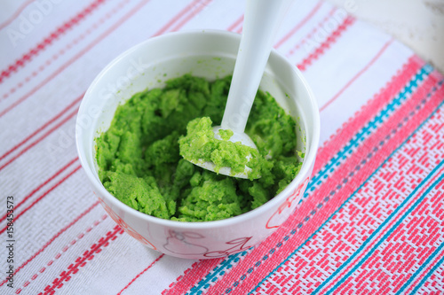 Broccoli puree in a white plate on a light background