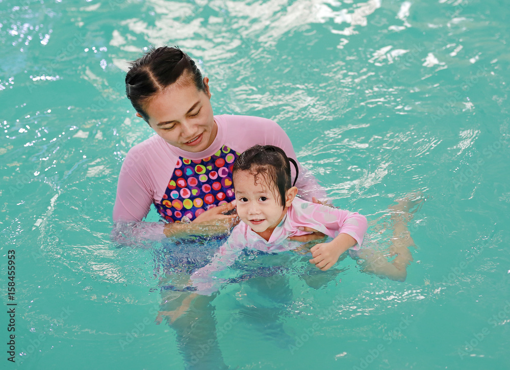 family of mother teaching kid in swimming pool. family of mother teaching kid in swimming pool.