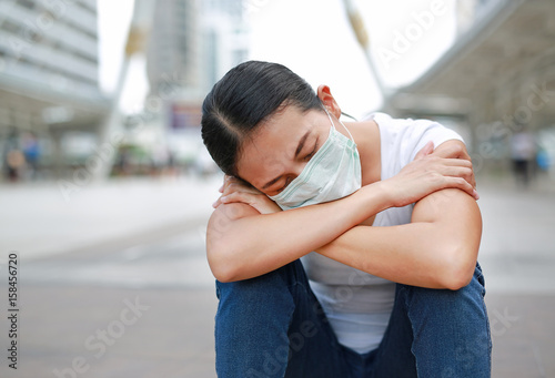Person wearing protective mask to protect pollution and the flu sitting at public area.