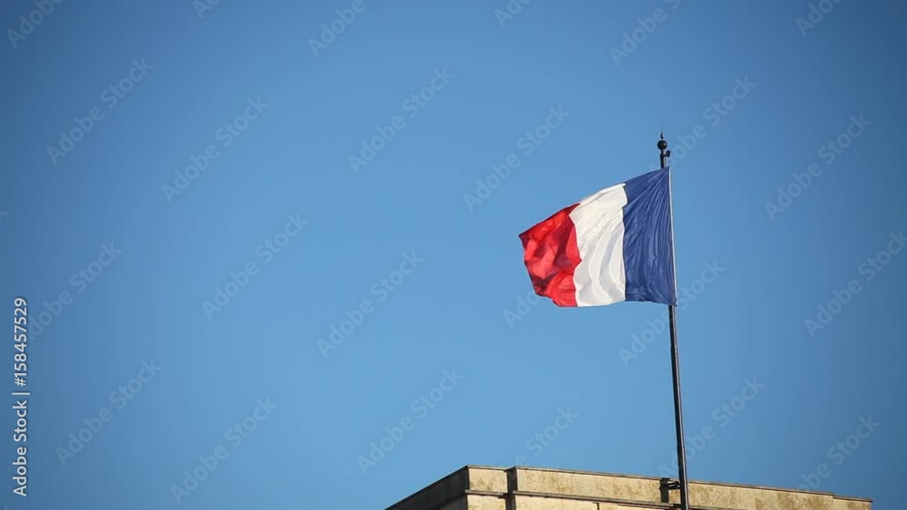 french flag waving on blue sky on top of the building