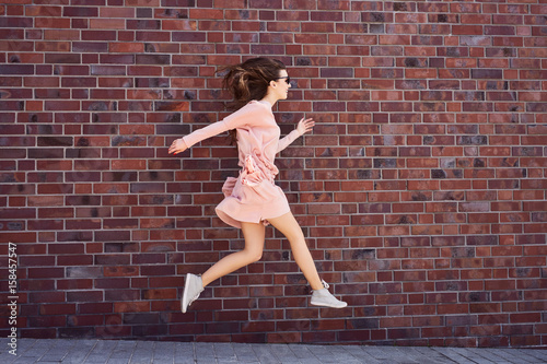 Joyful young woman jumping on the sidewalk