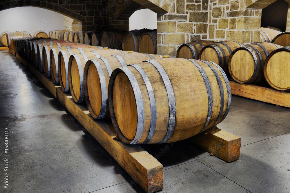 Wine barrels and metal cisterns in dark cellar Wine barrels and metal cisterns in dark cellar