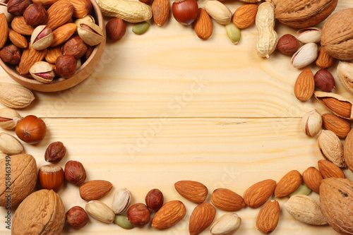 mix almonds, cashew nuts, hazelnut, peanuts, walnuts, pistachio on wooden background. Top view with copy space