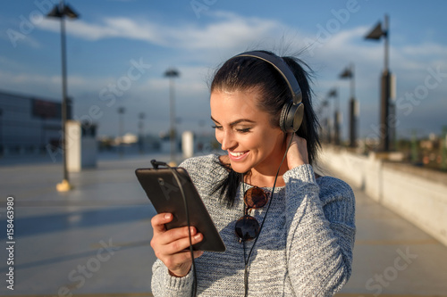Canvastavla Woman listening music by headphones and tablet outdoor