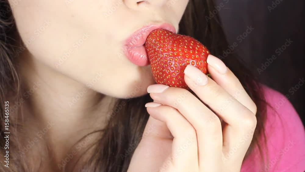 Sexy Woman Eating Strawberry in slowmotion. Sensual Red Lips. Red Manicure and Lipstick. Sexy Woman Eating Strawberry in slowmotion. Sensual Red Lips. Red Manicure and Lipstick.