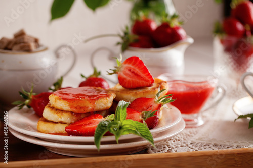Syrniki with strawberry and green tea cup on a light background