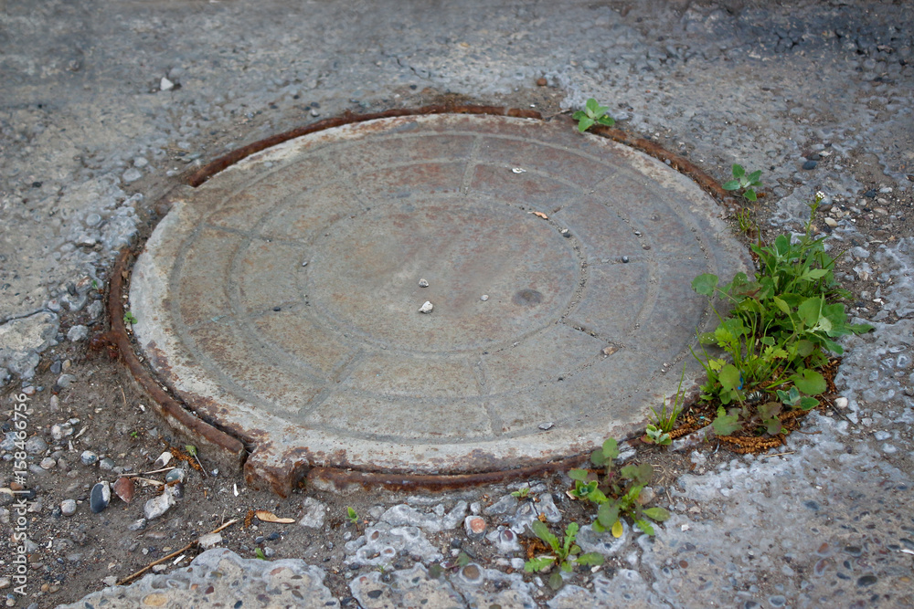 Old metal manhole. Closeup. The view from the top