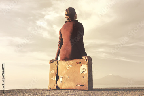 Traveler woman arriving at destination relaxes sitting on her suitcase