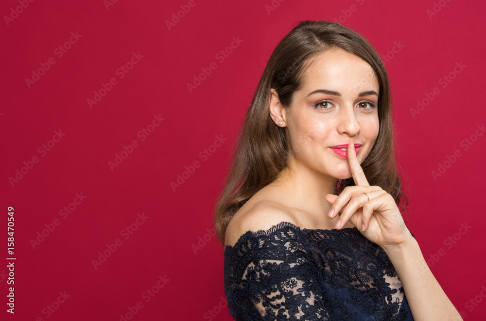 Beautiful girl looking at camera and holding finger near mouth Beautiful girl looking at camera and holding finger near mouth